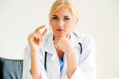 Bir tıp hap elinde tutan genç kadın doktor. Tıbbi sağlık kavramı.
