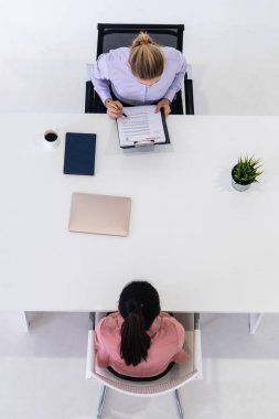 İş başvurusu ve iş anlaşması için ofis masasında toplanan iki genç iş kadını. İşe alım ve insan kaynakları kavramı.