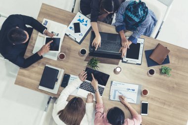 Modern ofisteki iş adamları ve iş kadınlarıyla grup toplantısındaki iş adamlarının en üst düzey görüşü, masada dizüstü bilgisayar, kahve ve belge ile. Şirket ortaklığı konsepti..