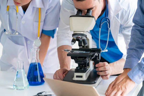 Group of scientists wearing lab coat working in laboratory while examining biochemistry sample in test tube and scientific instruments. Science technology research and development study concept.