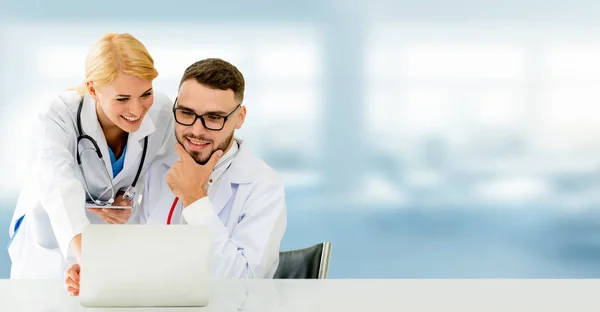 Doctor working with laptop computer at the office while having discussion with another doctor in the hospital. Medical healthcare and doctor service.