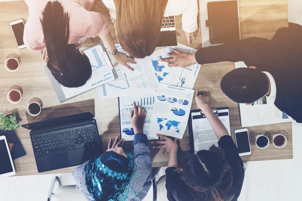 Modern ofisteki iş adamları ve iş kadınlarıyla grup toplantısındaki iş adamlarının en üst düzey görüşü, masada dizüstü bilgisayar, kahve ve belge ile. Şirket ortaklığı konsepti..