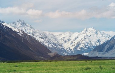 Dağ aralıkları ve yeşil çim çayır alan mavi gökyüzünde güneşli yaz günü beyaz bulutlar altında güzel manzara. Mt Cook, Yeni Zelanda en yüksek dağı vuruldu.
