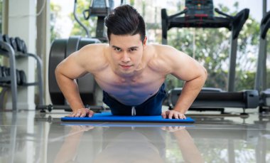 Fitness merkezinde itme yaparken vücut geliştirmeci genç adam. Sağlıklı yaşam tarzı ve vücut geliştirme kavramı.