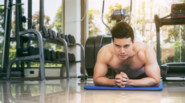 Fitness merkezinde itme yaparken vücut geliştirmeci genç adam. Sağlıklı yaşam tarzı ve vücut geliştirme kavramı.