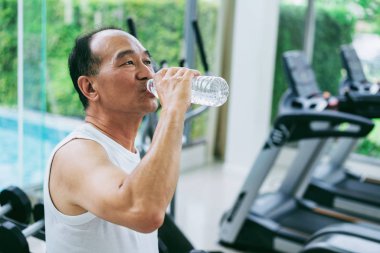 Komuta sizde spor salonu fitness merkezinde egzersiz sonrası maden suyu iç. Yaşlı sağlıklı yaşam tarzı.