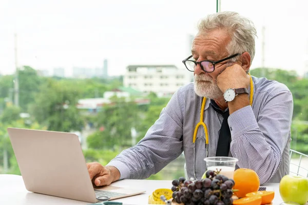 Médecin nutritionniste masculin senior travaillant sur ordinateur portable . — Photo