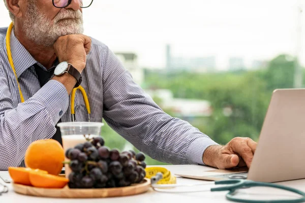 Senior médico nutricionista masculino que trabaja en el ordenador portátil . —  Fotos de Stock