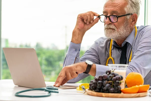 Senior médico nutricionista masculino que trabaja en el ordenador portátil . —  Fotos de Stock