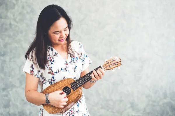 Boldog asszony zenész játszik ukulele stúdióban. — Stock Fotó