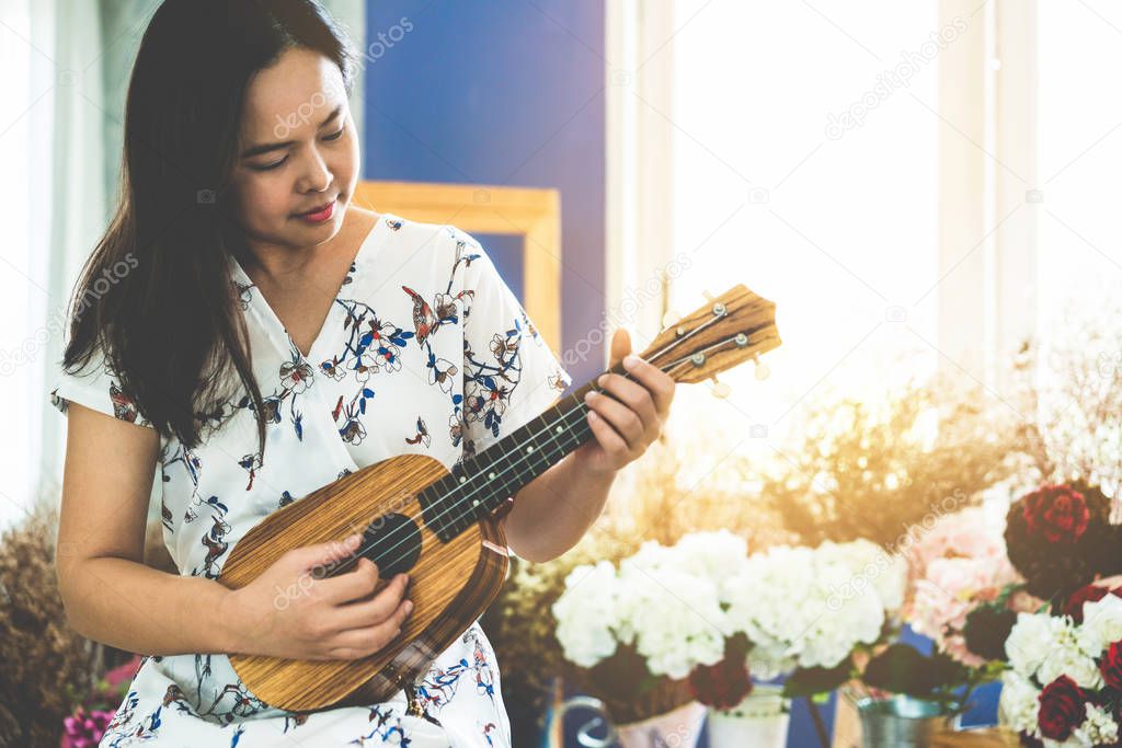 Happy woman musician playing ukulele in studio.