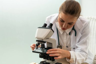 Hastane laboratuvarında mikroskop kullanan doktor.