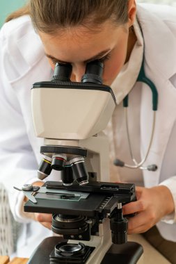 Hastane laboratuvarında mikroskop kullanan doktor.