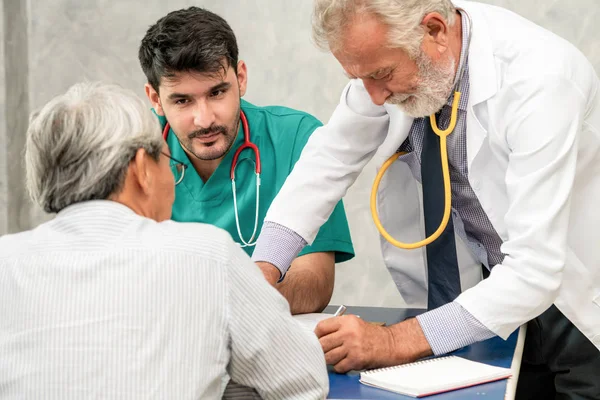 Mannelijke arts team praten met senior patiënt bezoek — Stockfoto