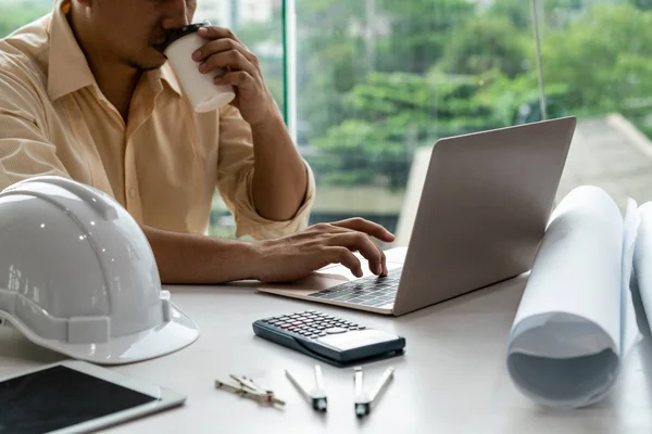 Young man architect or engineer working at desk.