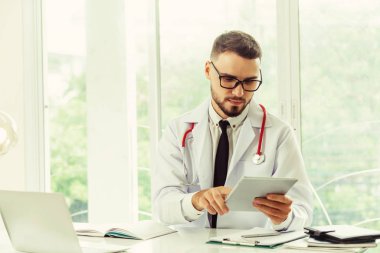 Hastanede tablet bilgisayar üzerinde çalışan doktor.