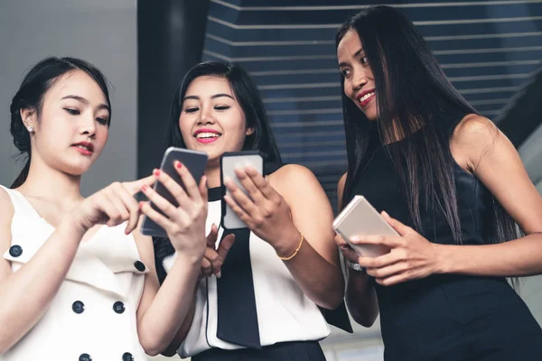 Three women friends chat with mobile phone device.