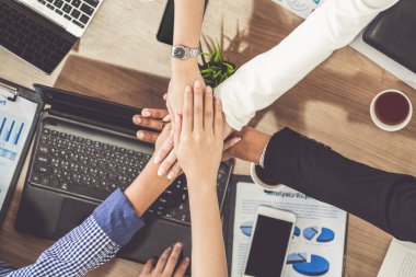 Takım çalışması çalışanları toplantıda el ele tutuşuyor.