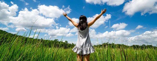 緑の草の上の若い女性が空に腕を広げる. — ストック写真