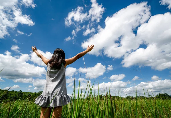 緑の草の上の若い女性が空に腕を広げる. — ストック写真