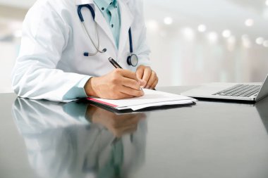 Doktor hastane ofisindeki belgelere yazıyor..