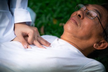 Doktor yerde baygın yaşlı adama yardım ediyor..