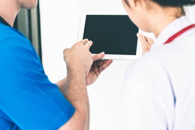 Doctors looking at data on computer at hospital. clipart