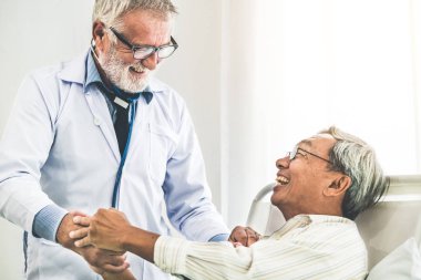 Hastane koğuşunda olgun doktor ve kıdemli hasta.