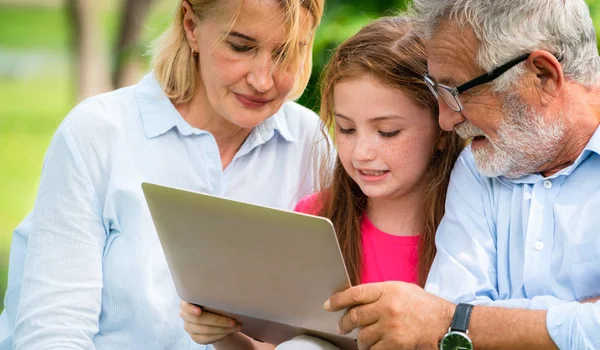 Família feliz usando computador portátil no parque público . — Fotografia de Stock