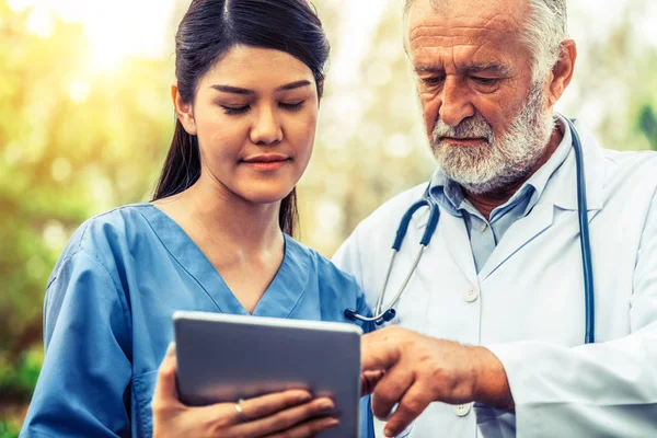 Médico senior y joven trabajando en el parque . —  Fotos de Stock