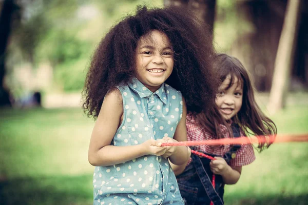 Crianças felizes jogando rebocador de guerra no parque . — Fotografia de Stock