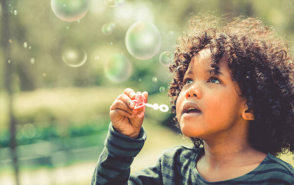Счастливый маленький ребенок, пускающий пузырь в школьном саду
.