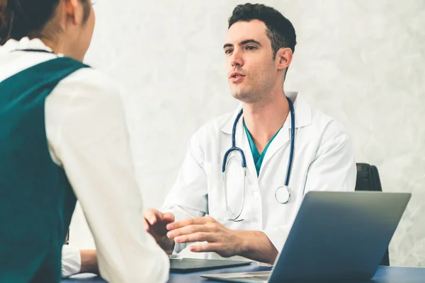 Jovem médico examinando paciente em consultório hospitalar . — Fotografia de Stock