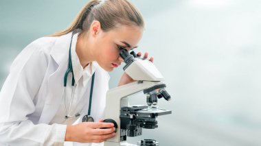 Bilim adamı araştırmacı laboratuvarda mikroskop kullanır