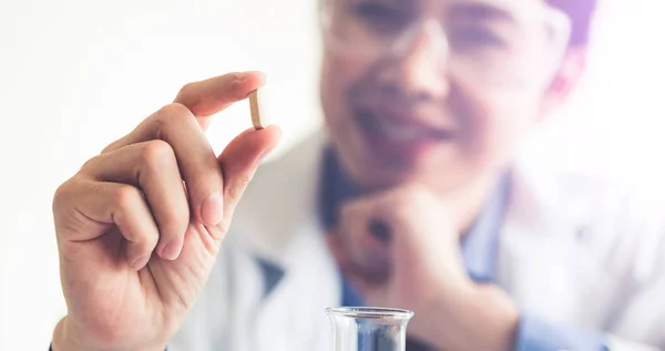 Doctor or scientist holding medicine pill in lab.