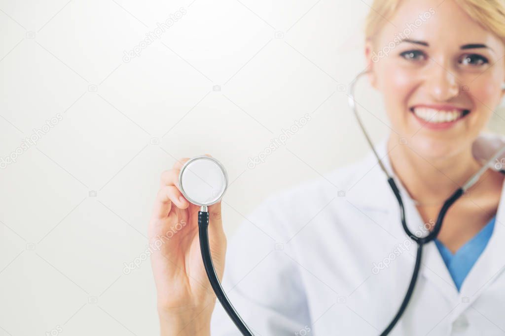 Female doctor pointing stethoscope at blank space.