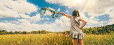 Yeşil çimenler üzerinde genç kadın gökyüzüne silah yayan.