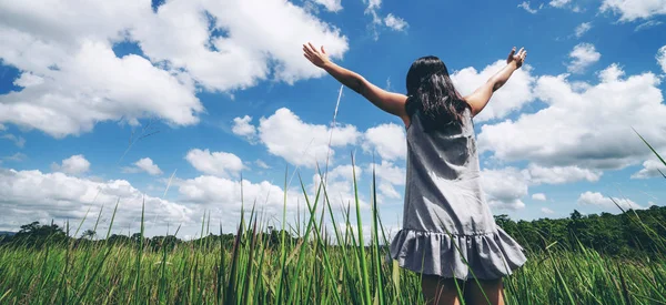 緑の草の上の若い女性が空に腕を広げる. — ストック写真