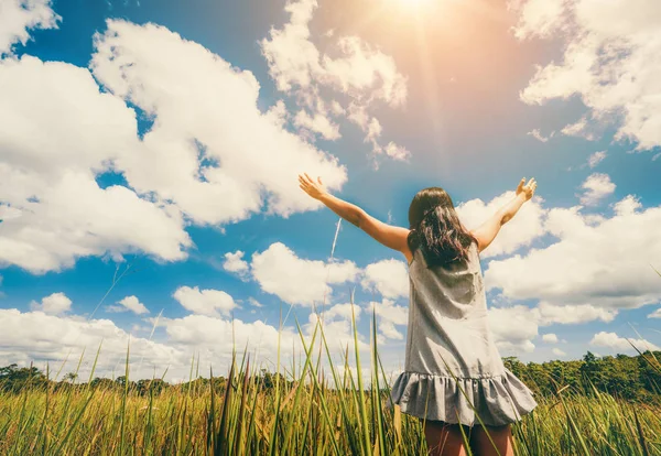 緑の草の上の若い女性が空に腕を広げる. — ストック写真
