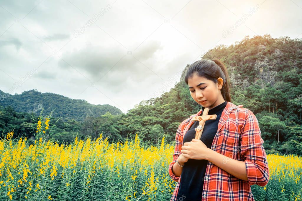 Young beautiful woman praying on nature background