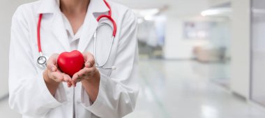 Hastane ofisinde kırmızı kalp tutan doktor.