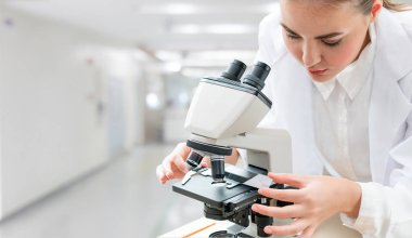 Bilim adamı araştırmacı laboratuvarda mikroskop kullanır
