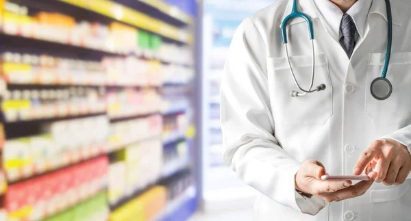 Farmacista maschio utilizzando il telefono cellulare in farmacia . — Foto Stock