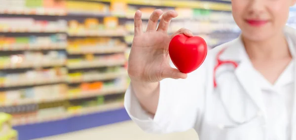 Doctor sosteniendo un corazón rojo en la oficina del hospital . — Foto de Stock