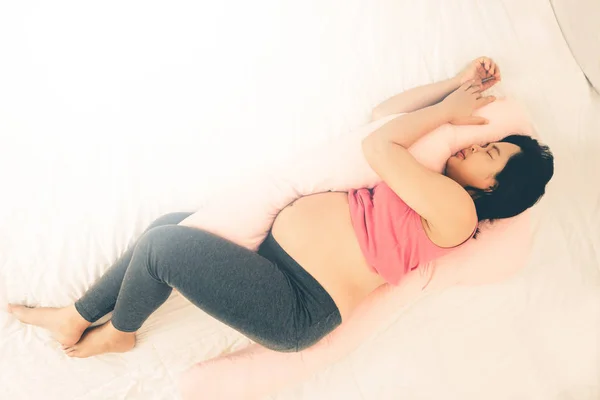 Heureuse femme enceinte dormant sur le lit dans la chambre. — Photo