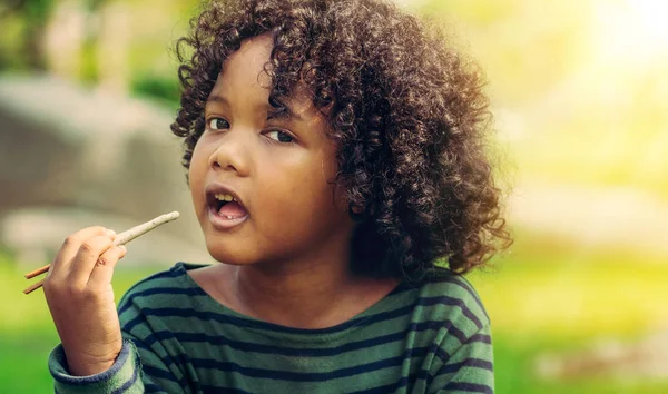 Feliz afroamericano niño comiendo snack stick . — Foto de Stock