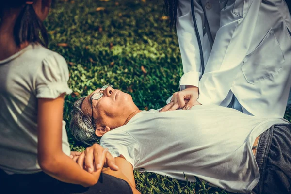 Doctor ayudando a un anciano desmayado en el suelo . — Foto de Stock