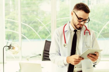 Hastanede tablet bilgisayar üzerinde çalışan doktor.