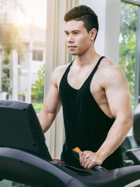 Spor salonunda koşu bandıüzerinde çalışan sportif koşucu.