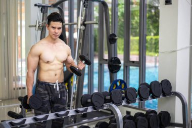 Kaslı adam vücut geliştirmeci dumbbells ile eğitim.